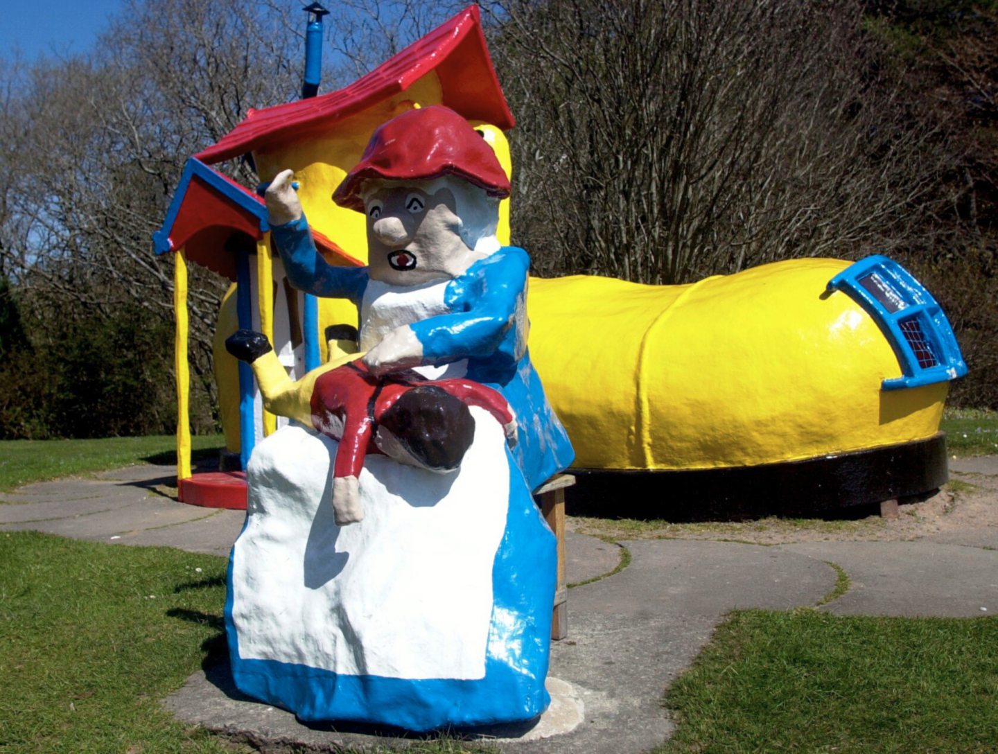 The Old Lady smacking a child over her lap in front of her shoe house