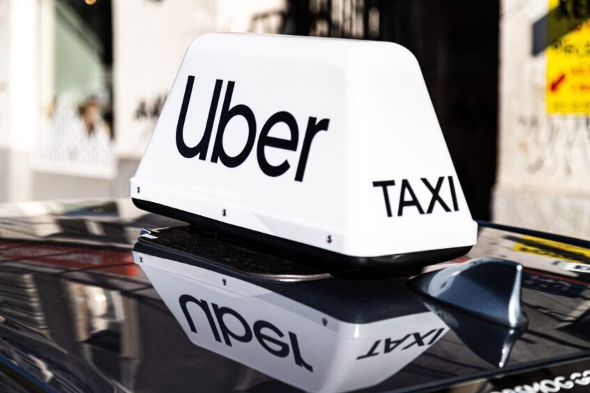 Uber Taxi sign on car.