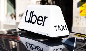 White Uber taxi sign on top of black vehicle.