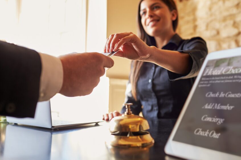 Guest takes room key card at check-in desk of hotel