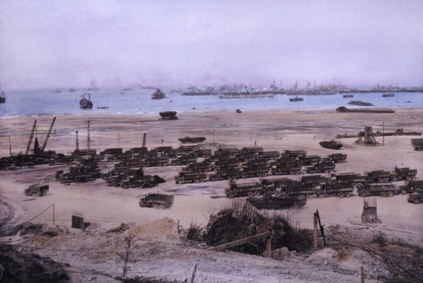 How Omaha beach looked on D Day with advancing boats and lines of tanks.