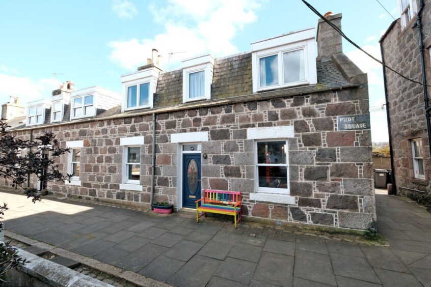 The fittie home with a rainbow coloured Dolly Parton themed bench outside