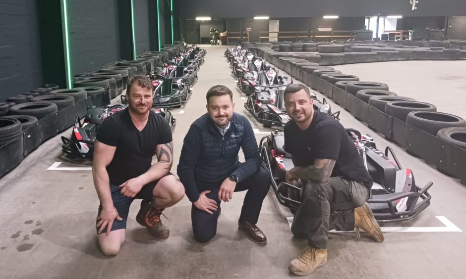 Bruce Porter, Reis Robertson and Allan Smith kneeling in front of go-karts.