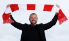 Aberdeen manager Jimmy Thelin raises a club scarf at Pittodrie.