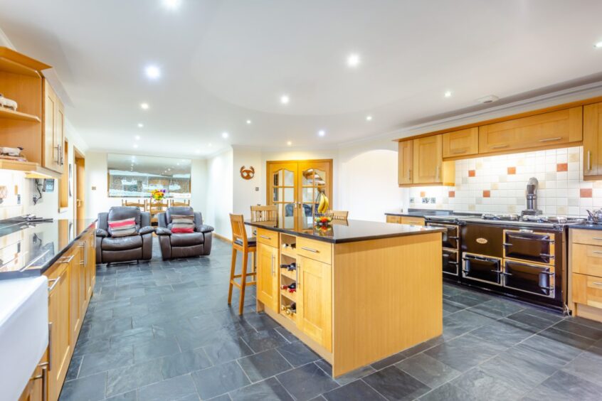 The Thurso property's kitchen area, with Aga oven, granite worktops, modern integrated appliances and  large central island with breakfast bar.