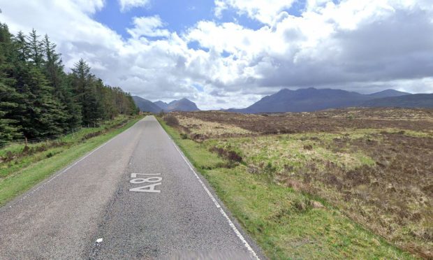 Cars travelling on the A87 north of Sligachan surrounded by fields and hills.