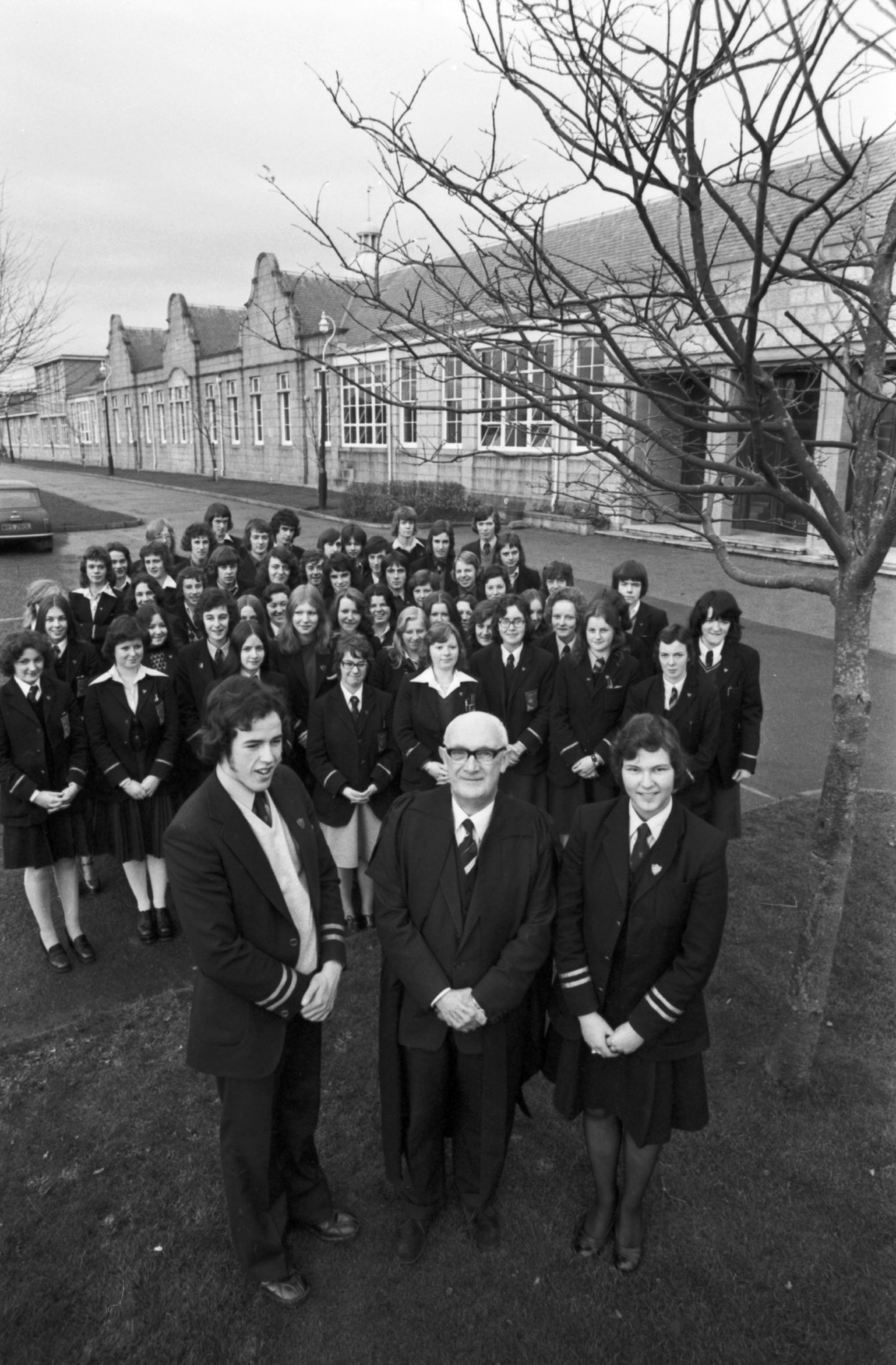 Dr Norman Dixon with the captains of the school, Graeme Reid and Morag Shiach, with prefects behind standing outside the school