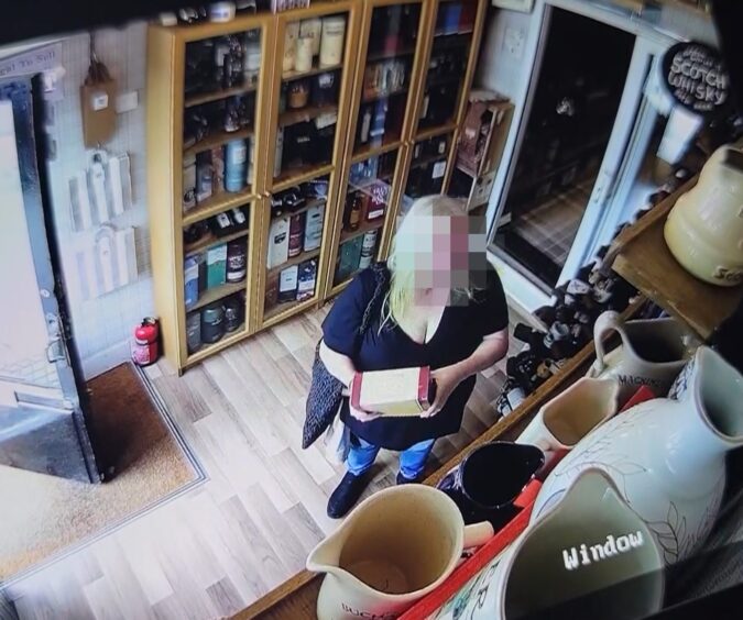 Screengrab from video footage of woman shoplifting a bottle at Ballater whisky store Caledonian Collectables.
