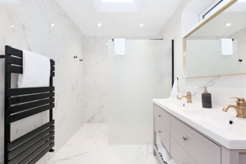 The bathroom in the Aberdeen home renovation with white marble walls and flooring and black and gold accents