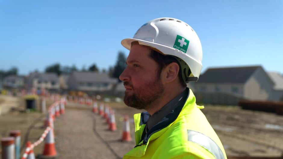 man wearing hard hat that reads 'first aider'