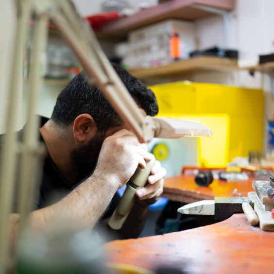 man at in-store workshop looks through a piece of equipment to examine jewellery