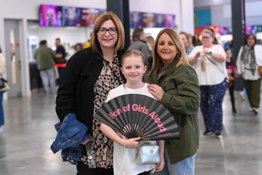 Revellers pose for pictures with a Girls Aloud hand fan ahead of the concert in Aberdeen