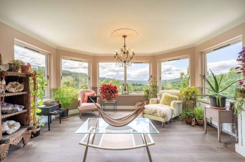 Large open plan sitting room with cream walls and large windows overlooking the mountain view.