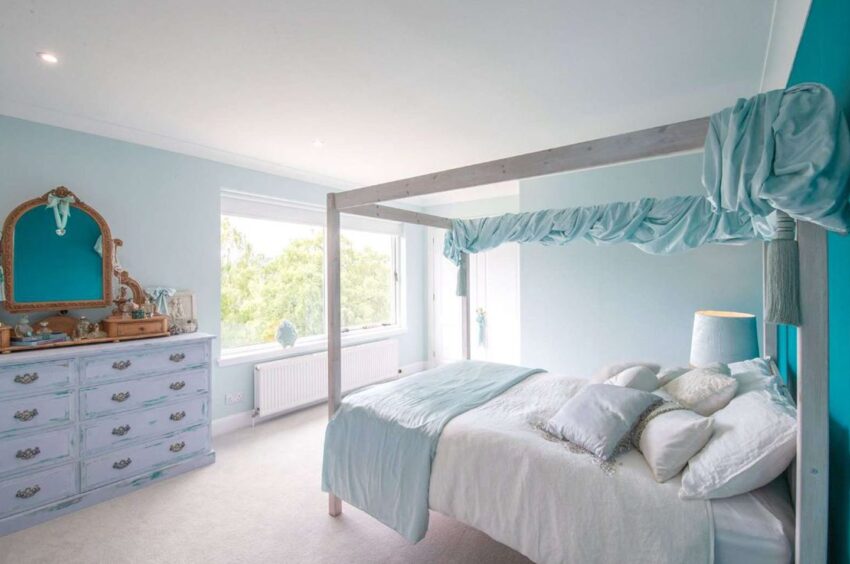 A bright bedroom with four poster bed with a light blue colour scheme.