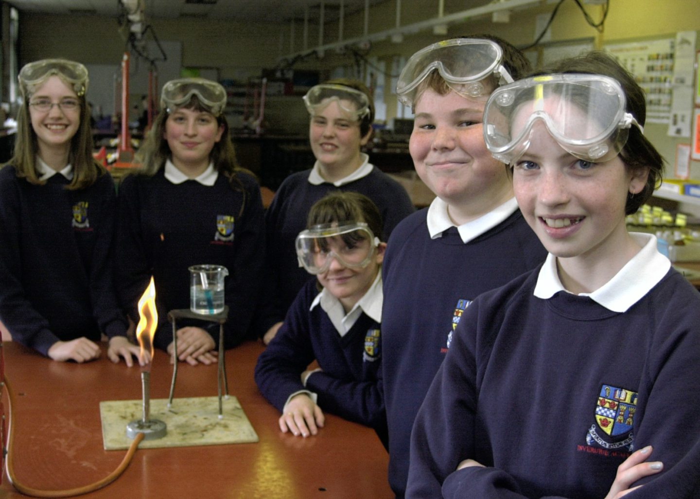 Inverurie Academy science club posing for photos with goggles on gathered around a Bunsen burner