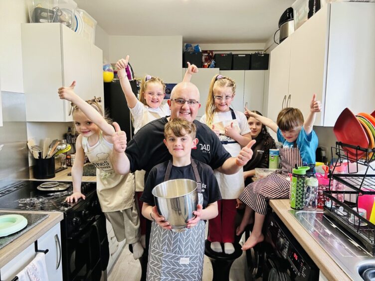 Ben and six of the Sullivan Family kids preparing a meal in the kitchen.