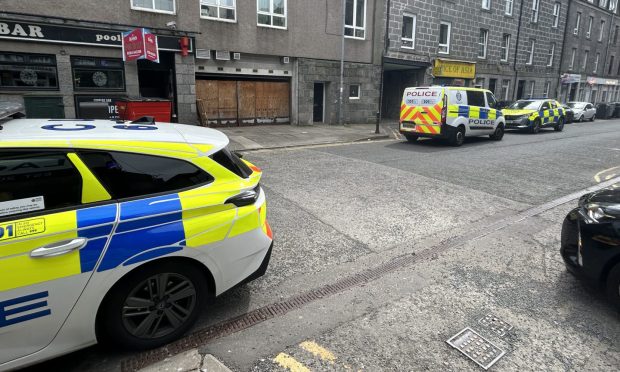 Two police cars and a police van parked on John Street