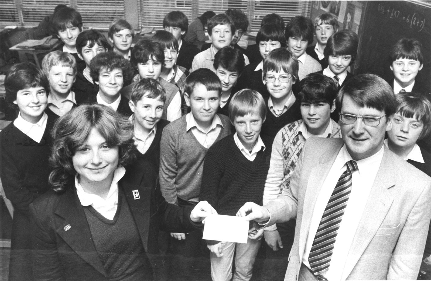 Pupils standing behind a student handing a cheque to Barry Middleton