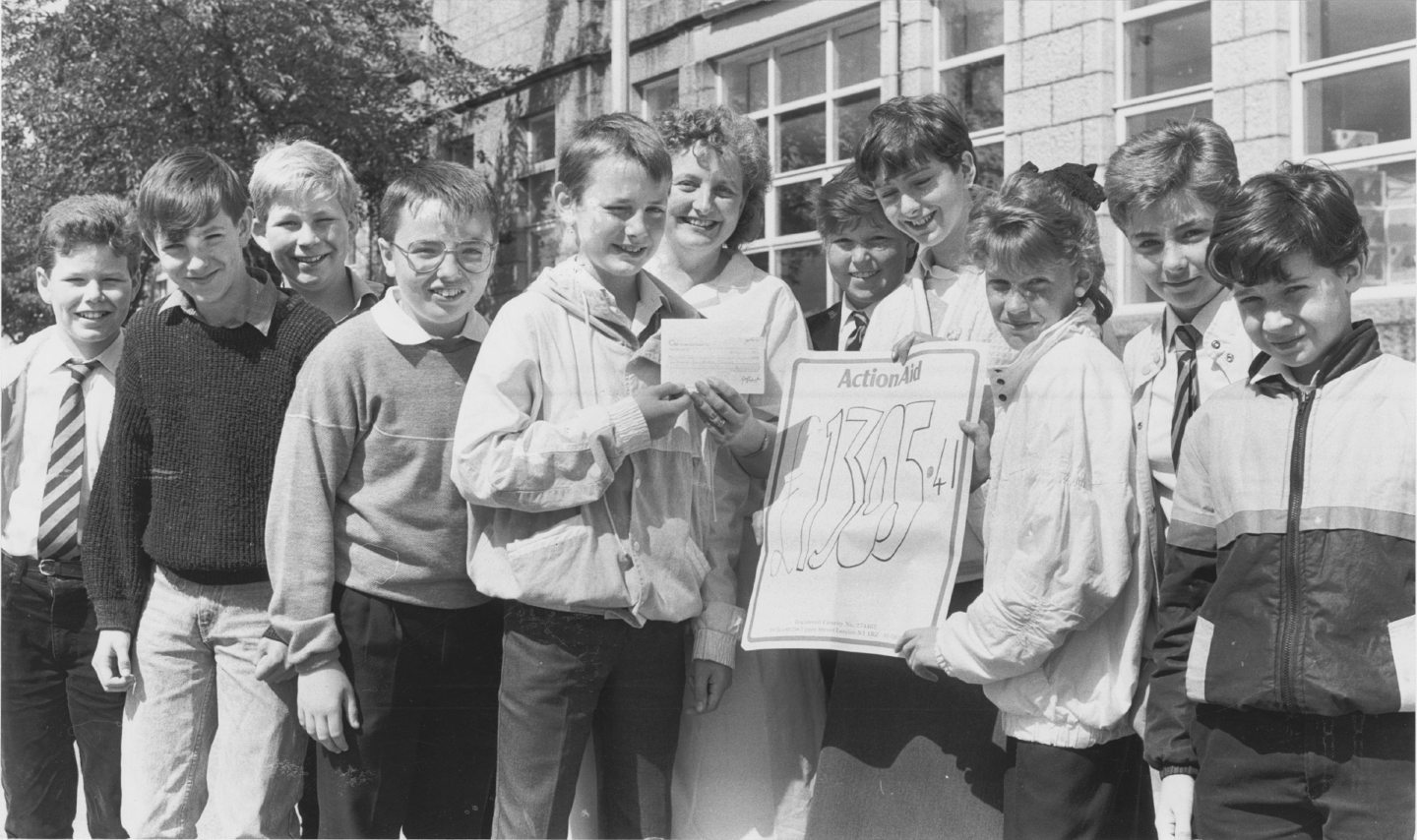 Young pupils holding a cheque and poster