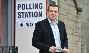 Douglas Ross with polling station sign behind.