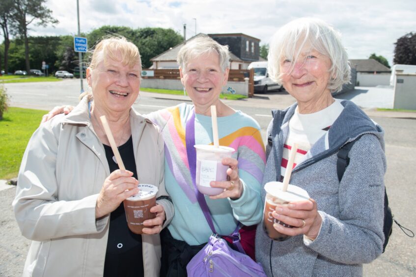 Three women holding their bubble tea