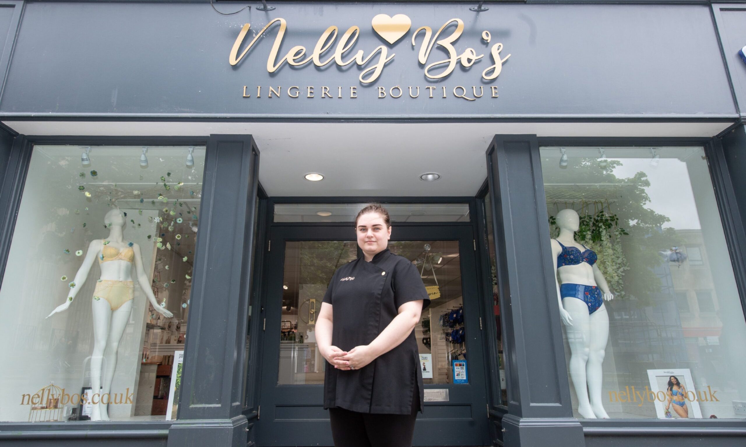 Kerry Dean in front door of Nelly Bo's under shop sign. 