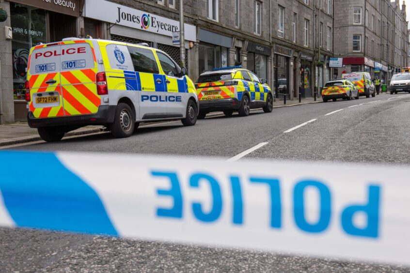 Police cordon tape with police cars in background