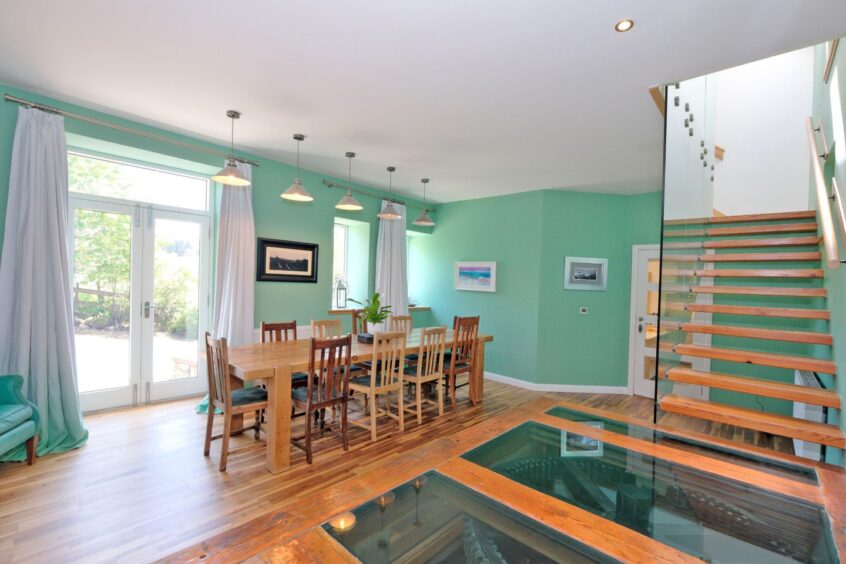 Open plan dining hallway at the Renovated Inverurie mill, featuring glass floor with the illuminated mill clogs below.