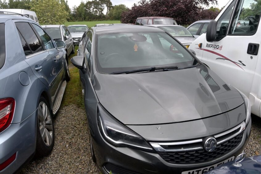 Grey Vauxhall Astra sits in a garage yard awaiting repair.