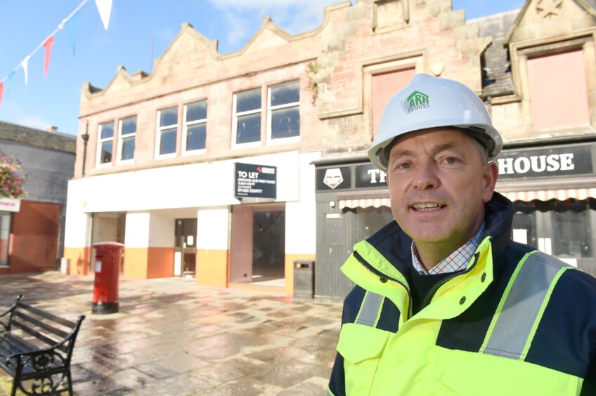 William Gray dressed in a white hard hat and fluorescent jacket.