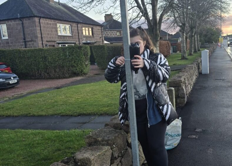 Daughter Megan placing a dog bag dispenser in Dyce.