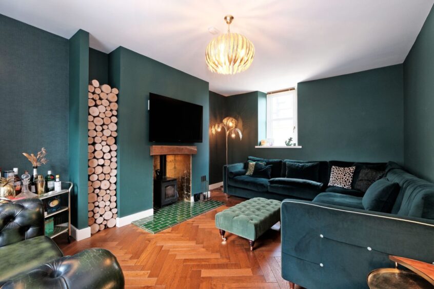 The living room of the home, with shades of dark green and wood tones