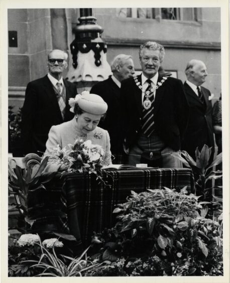 Queen Elizabeth II signing the visitor's book at Inverness Town House during her 1985 visit. 