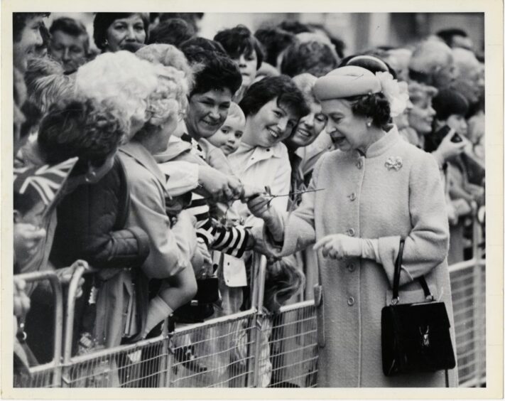 Queen Elizabeth receives a rose from a well wisher during her walkabout.