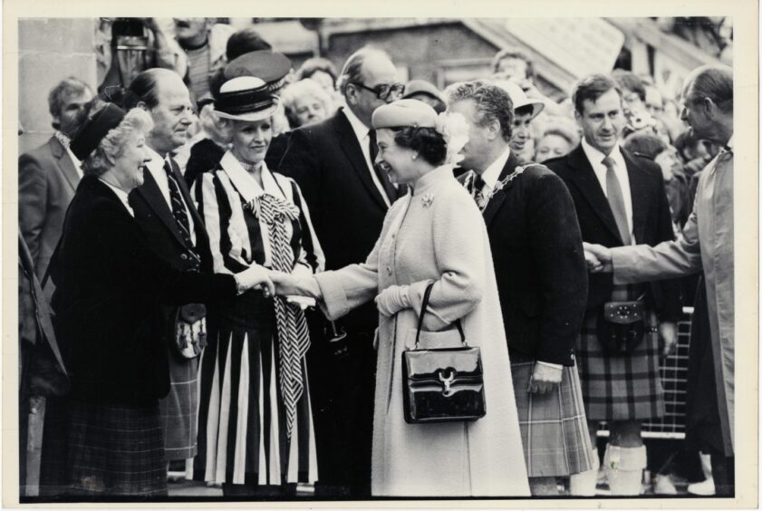 The late queen shakes the hand of a local dignitary.