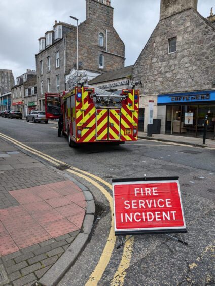 Red Fire Service incident sign sits to the rear of a fire engine on Rose Street.