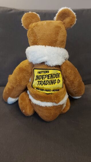 Brown and white memory bear with a yellow badge on the back.