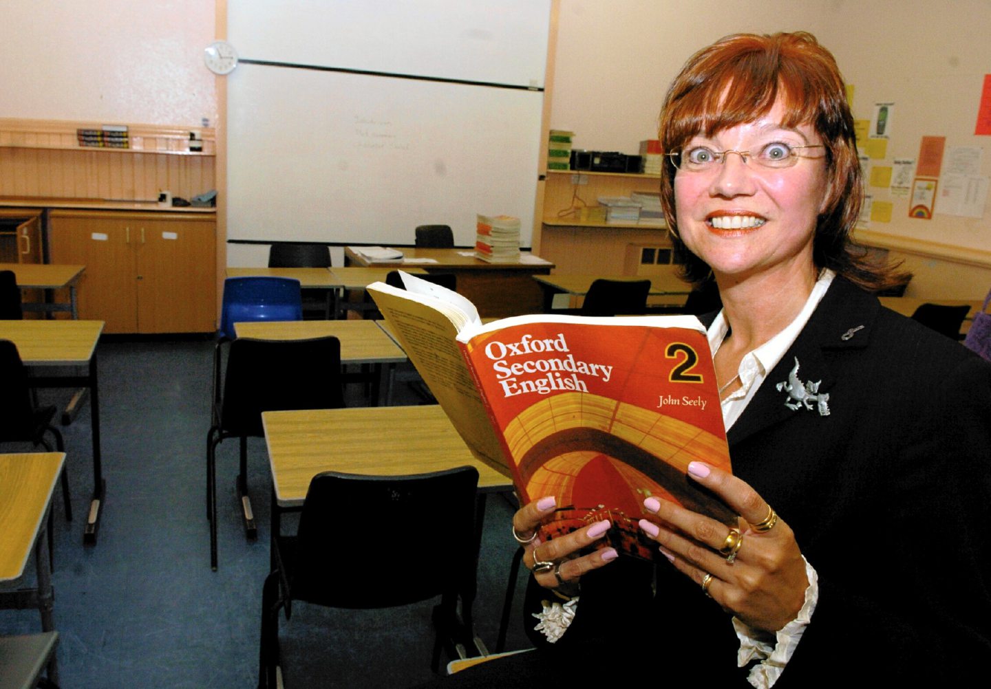 A teachers in her classroom holding a textbook