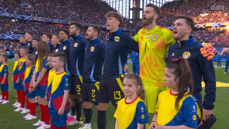 Screenshot of TV screen as the Scotland squad and mascots sang the national anthem 