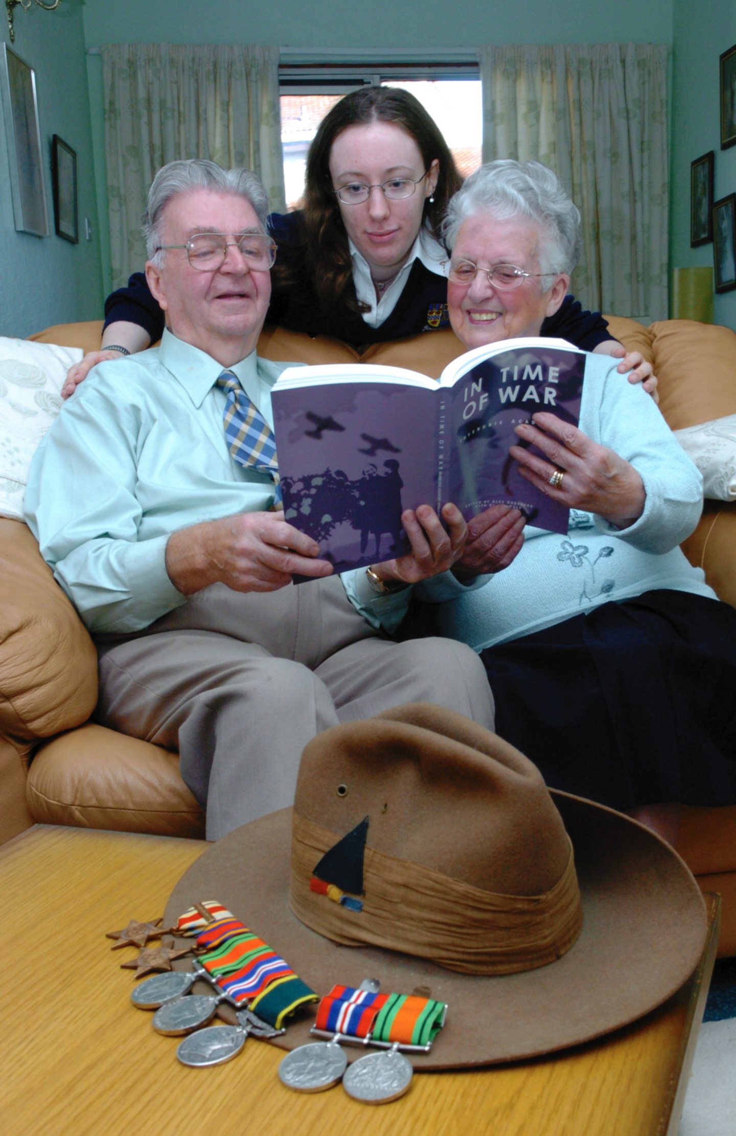 A Pupil with two elderly people holding a book about war