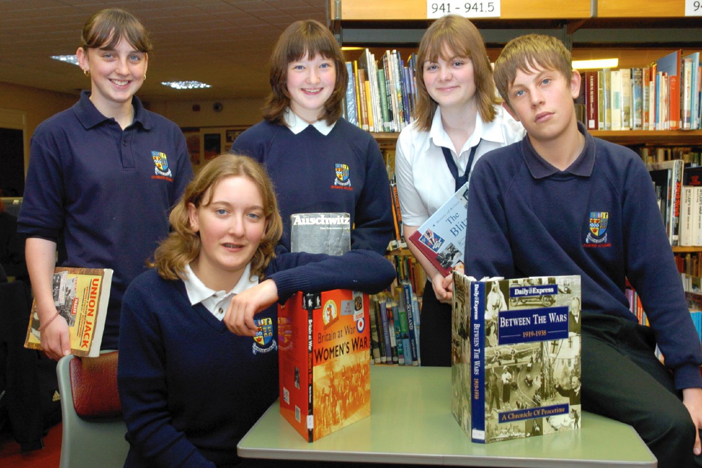 Inverurie Academy pupils posing for photos in the library with some books about war