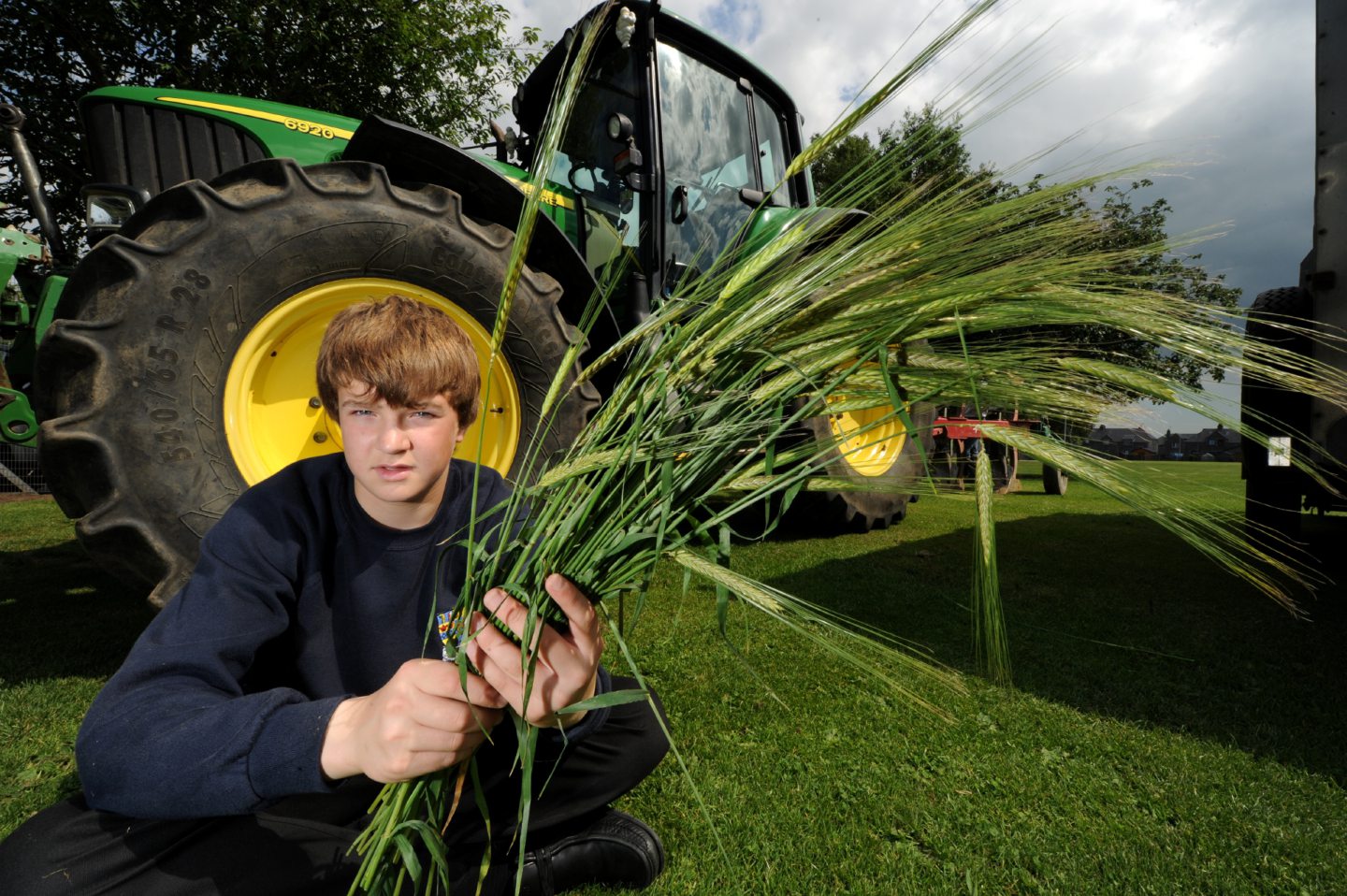 A pupil holding crops in front of a tractor