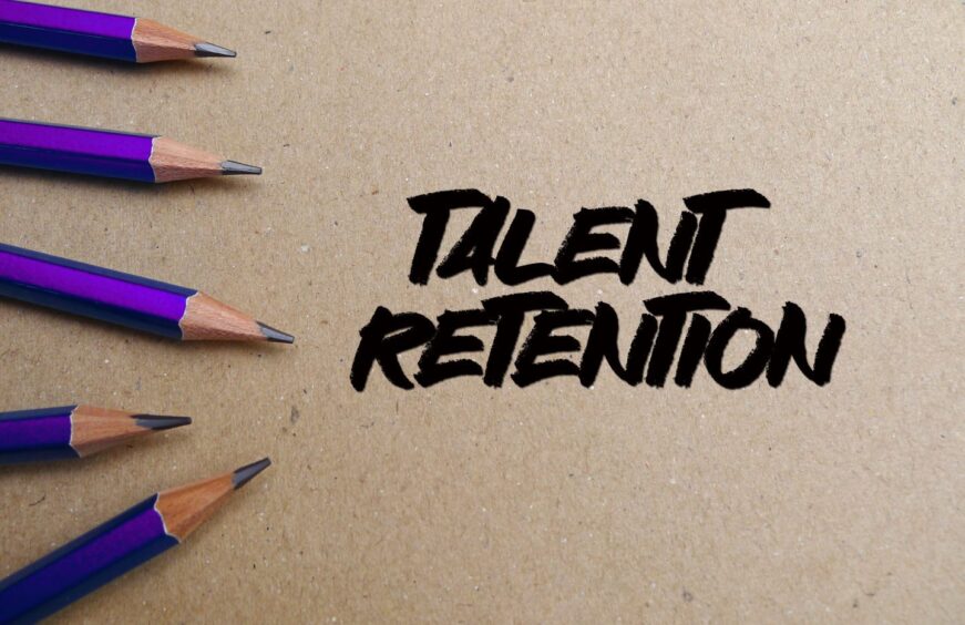 Word text Talent Retention memo written on a brown craft paper as background with purple pencils
