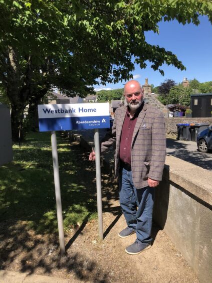 Councillor Derek Ritchie standing next to Westbank Care Home sign.