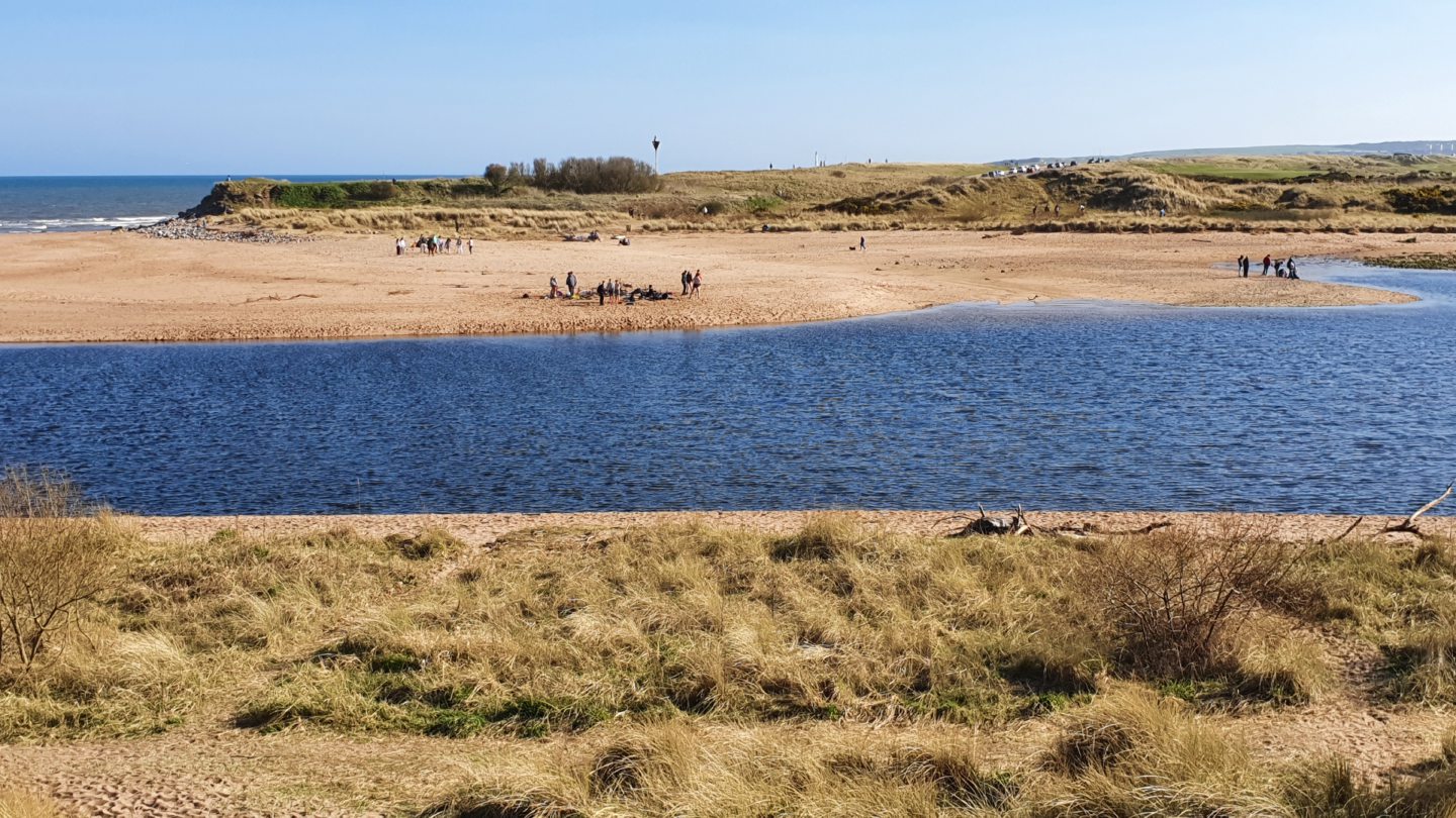 People enjoying the sunshine at Donmouth where the River Don meets the sea.