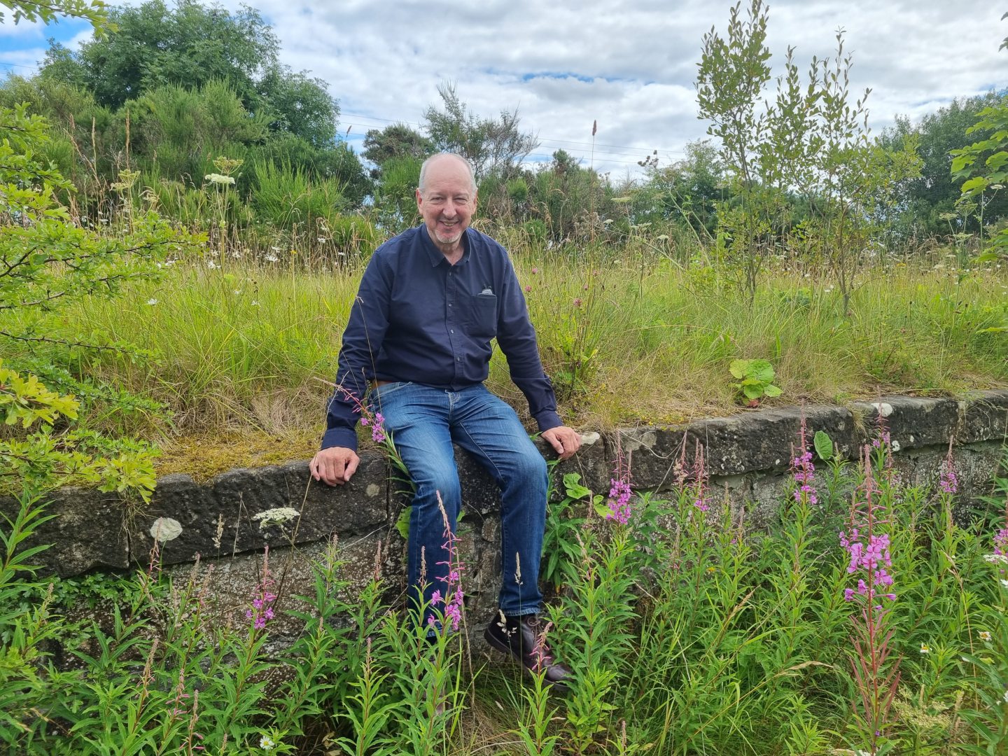 Mark Nolan sitting on the now overgrown old goods platform at Fearn station.