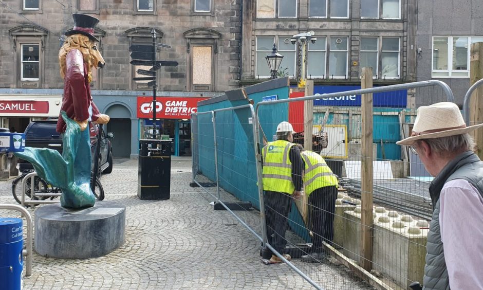 Workmen removing hoarding outside Poundland. 