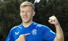 Former Aberdeen midfielder Connor Barron points to the Rangers badge on his shirt as he signs for the Ibrox club.