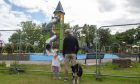 Man and child with dog looking at playpark