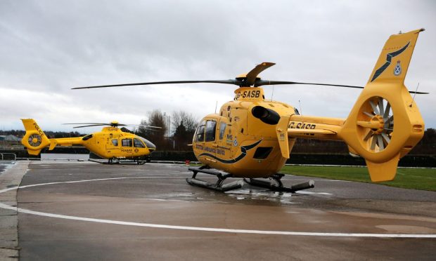 Two yellow air ambulances on a helicopter pad.